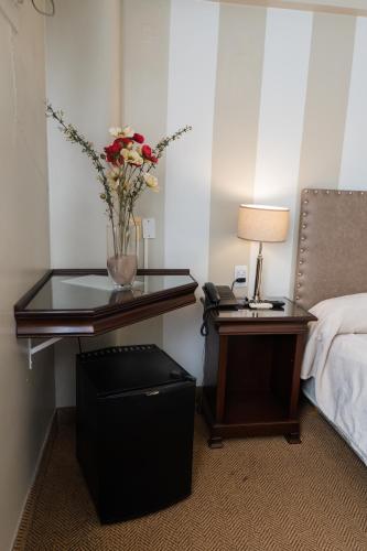 a bedroom with a table with a vase of flowers on it at Hotel Embajador in San Miguel de Tucumán