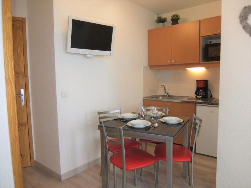une cuisine avec une table avec des chaises et une télévision au mur dans l'établissement Apartment Médian 005 by Interhome, aux Menuires