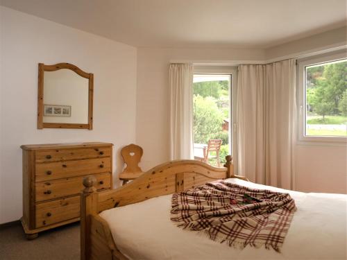 a bedroom with a bed and a dresser and a window at Apartment Chesa Flora 53 by Interhome in St. Moritz