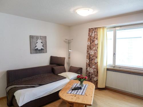Schlafzimmer mit einem Bett, einem Tisch und einem Fenster in der Unterkunft Apartment Chesa Ova Cotschna 305 by Interhome in St. Moritz