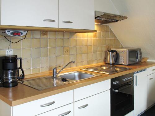 eine Küche mit einer Spüle und einer Mikrowelle in der Unterkunft Apartment Alte Molkerei-2 by Interhome in Friederikensiel