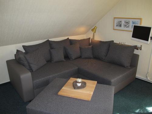 ein Wohnzimmer mit einem grauen Sofa und einem Tisch in der Unterkunft Apartment Alte Molkerei-2 by Interhome in Friederikensiel