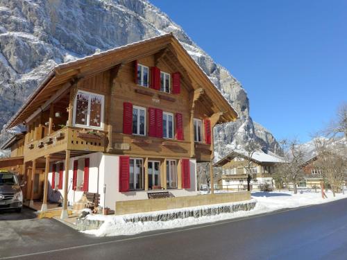 a wooden house with red shutters in front of a mountain at Apartment Rösli by Interhome in Stechelberg