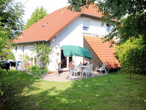 a group of people sitting at a table under a green umbrella at Holiday Home Mee - hrzeit - HOK106 by Interhome in Hooksiel