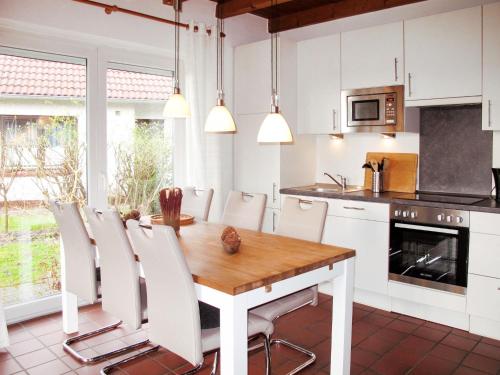 a kitchen with a wooden table and white chairs at Holiday Home Mee - hrzeit - HOK106 by Interhome in Hooksiel