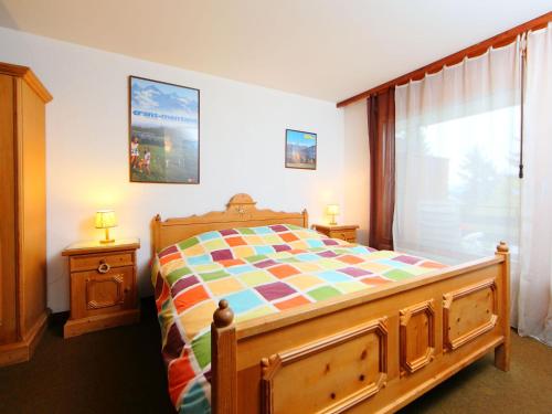 sypialnia z drewnianym łóżkiem i oknem w obiekcie Apartment Yuca B-2 by Interhome w mieście Crans-Montana