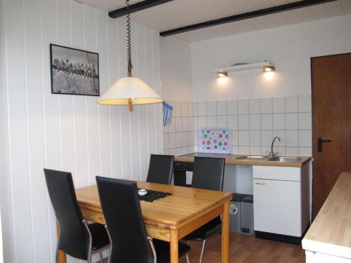 eine Küche und ein Esszimmer mit einem Holztisch und Stühlen in der Unterkunft Holiday Home Osterkamp by Interhome in Friederikensiel