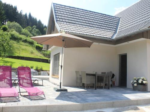 a patio with pink chairs and a table and an umbrella at Holiday Home am Bächle by Interhome in Hofstetten