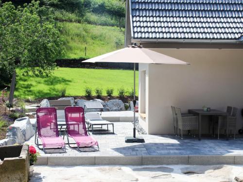 a patio with two pink chairs and an umbrella at Holiday Home am Bächle by Interhome in Hofstetten