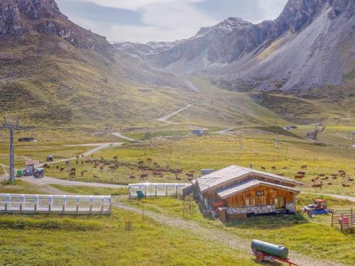 um celeiro num campo com montanhas ao fundo em Apartment Les Tommeuses - Val Claret-19 by Interhome em Tignes