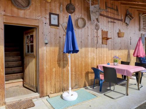 uma mesa com um guarda-chuva azul ao lado de uma parede de madeira em Apartment Grossen by Interhome em Frutigen