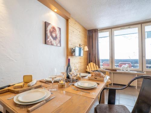 Studio Les Grandes Platières-11 by Interhome في تينيِ: غرفة طعام مع طاولة مع الأطباق وكؤوس النبيذ