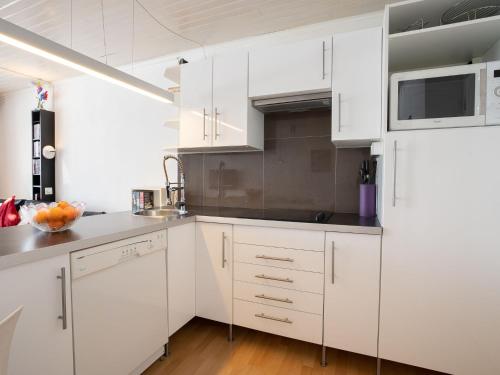 une cuisine blanche avec des armoires blanches et un micro-ondes dans l'établissement Apartment Neige d'or - Val Claret-2 by Interhome, à Tignes