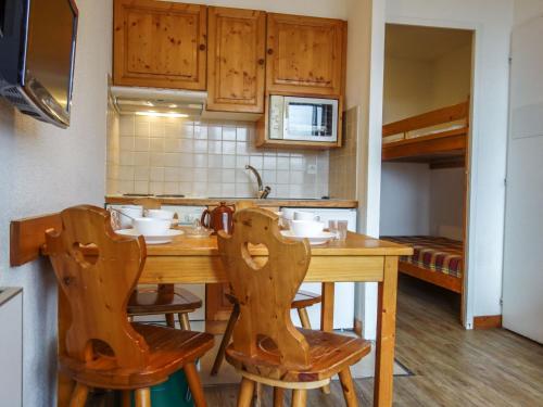 une cuisine avec une table en bois et deux chaises dans l'établissement Apartment Home Club - Lavachet-1 by Interhome, à Tignes
