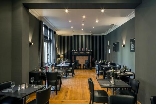 a restaurant with black tables and chairs and a fireplace at Hotel Le Cygne d'Argent in Liège