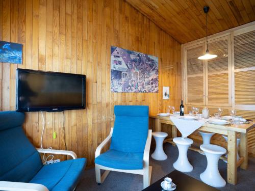 um quarto com uma mesa, uma televisão e uma cadeira azul em Apartment Le Curling B-22 by Interhome em Tignes