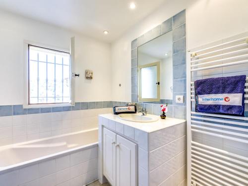 La salle de bains blanche est pourvue d'un lavabo, d'une baignoire et d'une baignoire. dans l'établissement Holiday Home Les Migraniers by Interhome, à Grimaud