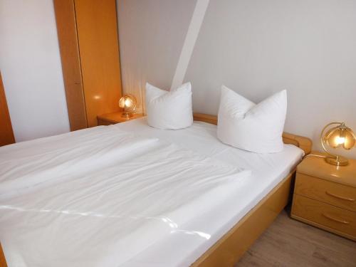 a white bed with two pillows on top of it at Apartment Schwarzwaldblick-13 by Interhome in Obertal