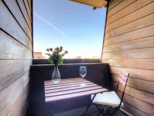 a table with two glasses and a vase of flowers on a balcony at Studio Les Marinas-4 by Interhome in Deauville