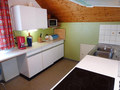 eine kleine Küche mit weißen Schränken und einem Waschbecken in der Unterkunft Apartment Haus Silberdistel by Interhome in Gersbach