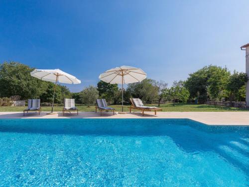 a swimming pool with two umbrellas and two chairs at Holiday Home Lancin - RCA452 by Interhome in Marčana