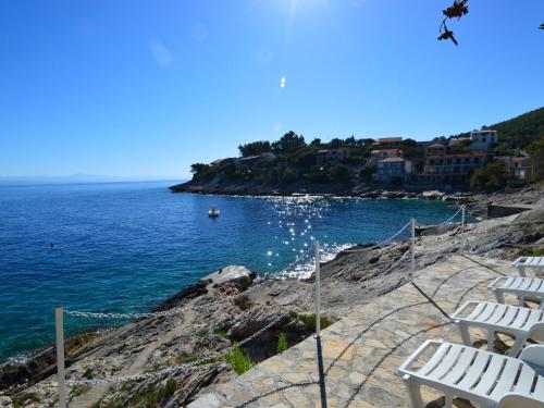 a group of white chairs sitting on a cliff near the ocean at Apartment Borovina-2 by Interhome in Prigradica