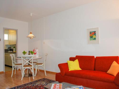 ein Wohnzimmer mit einem roten Sofa und einem Tisch in der Unterkunft Apartment Residenza Lido-20 in Locarno