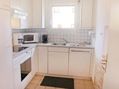 een keuken met witte kasten, een wastafel en een raam bij Apartment Chesa Sur Val 22 by Interhome in St. Moritz