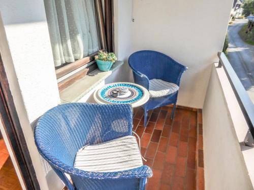 Duas cadeiras azuis e uma mesa na varanda em Apartment Der Malerwinkel-3 by Interhome em Enkirch