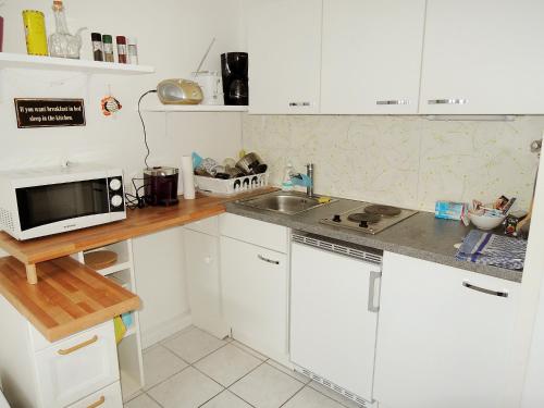 a kitchen with white cabinets and a sink and a microwave at Apartment Am Margaretenplatz by Interhome in Vienna