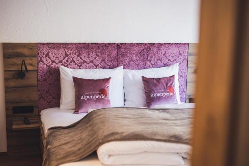 a bed with a purple headboard and pillows at Alpenperle Apartments in Ladis
