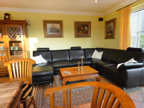 ein Wohnzimmer mit einem schwarzen Ledersofa und einem Tisch in der Unterkunft Holiday Home Seeadler by Interhome in Groß Zicker