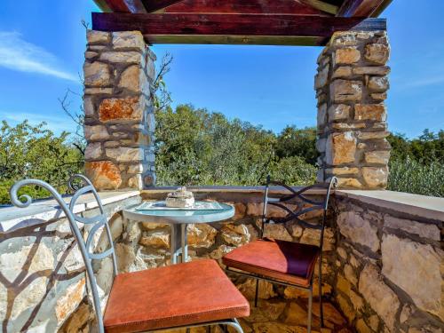 eine Terrasse mit einem Tisch und Stühlen an einer Steinmauer in der Unterkunft Holiday Home Samo by Interhome in Buroli