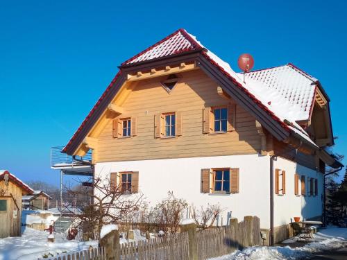a house with a wooden roof in the snow at Apartment Ahorn in Schönbronn