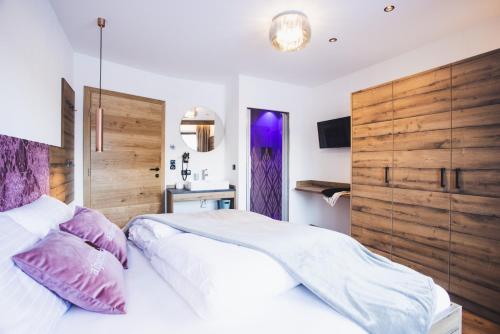 a bedroom with a large white bed with purple pillows at Alpenperle Apartments in Ladis