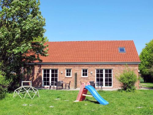 una casa con un parque infantil con un tobogán en el patio en Holiday Home Altes Schöpfwerk-4 by Interhome, en Bunde