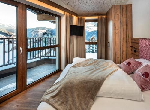 a bedroom with a bed and a balcony with mountains at Alpenperle Apartments in Ladis