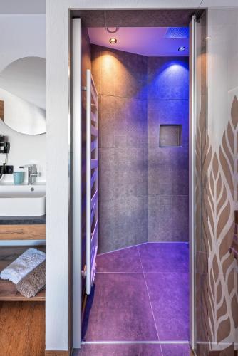 a bathroom with purple flooring and a walk in shower at Alpenperle Apartments in Ladis