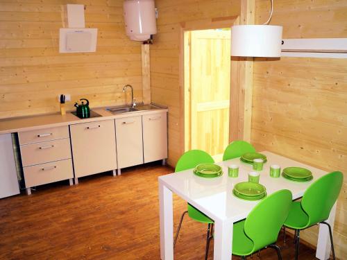 cocina con mesa blanca y sillas verdes en Holiday Home Onyx-1 by Interhome, en Mielenko