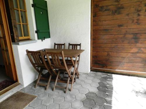 une table et des chaises en bois installées à côté d'une porte dans l'établissement Apartment Gletscherhorn II - Tapia by Interhome, à Zweisimmen