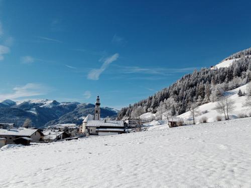 a snow covered hill with a town and a church at Apartment Sonnseit Living by Interhome in Oberau
