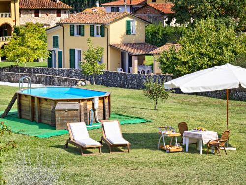 a pool with chairs and a table and an umbrella at Holiday Home Gli Antichi by Interhome in Camaiore