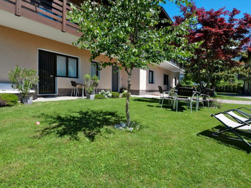 a yard with chairs and a tree in front of a building at Apartment Anna-1 by Interhome in Caldonazzo