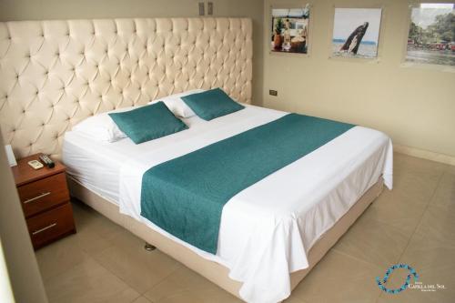a bedroom with a large white bed with blue pillows at Capilla Del Sol in Buenaventura