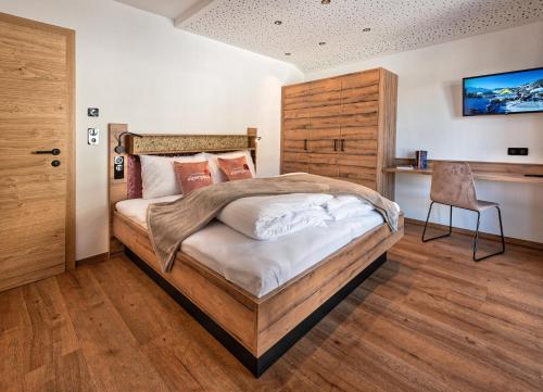 a bedroom with a large bed with a wooden headboard at Alpenperle Apartments in Ladis