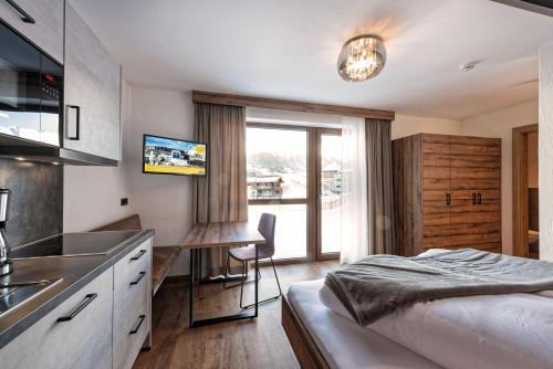 a bedroom with a bed and a kitchen with a window at Alpenperle Apartments in Ladis