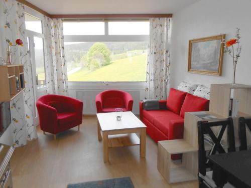 a living room with a red couch and chairs and a window at Apartment App- 1406 - Kurhotel Schluchsee by Interhome in Schluchsee