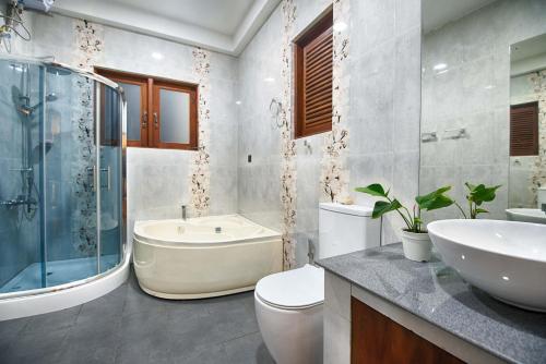 a bathroom with a tub and a toilet and a sink at Calypso Sunset in Iranawila