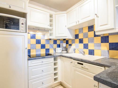 サントロペにあるApartment Eden Parc-4 by Interhomeの白いキャビネットと青と黄色のタイルが施されたキッチン