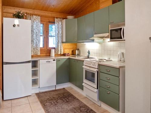 LahdenperäにあるHoliday Home Kurre by Interhomeのキッチン(緑のキャビネット、白い冷蔵庫付)